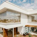 Exterior of contemporary cottage with large windows and stylish terrace against cloudy blue sky